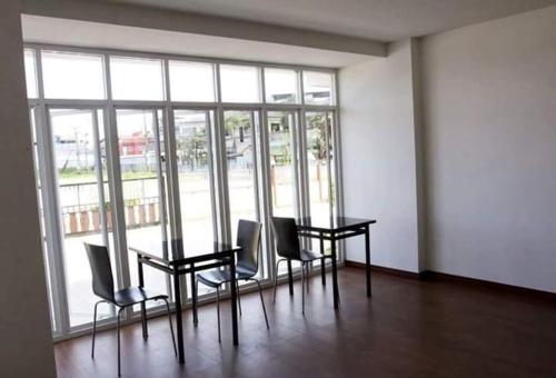 a room with a table and chairs and a large window at Field Town Apartment in Nakhon Nayok