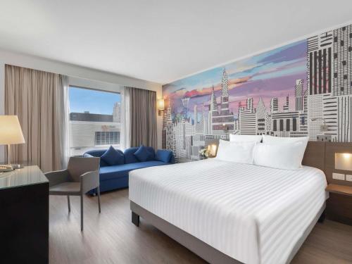 a bedroom with a large white bed and a blue couch at Novotel Bangkok on Siam Square in Bangkok