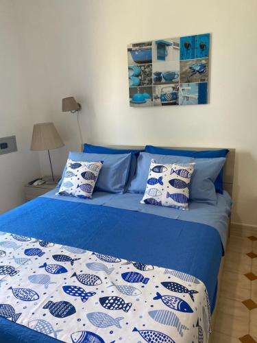 a bed with blue and white sheets and pillows at villa martina suite apartament in Lacco Ameno