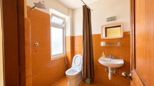 a bathroom with a toilet and a sink and a window at Hotel Sherwi Hyul in Kathmandu