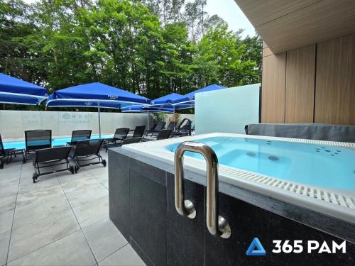 a swimming pool with chairs and blue umbrellas at 365PAM - Apartament Sea & Forest - BASEN KRYTY I ZEWNĘTRZNY, JACUZZI, SAUNA, GARAŻ W CENIE in Międzyzdroje