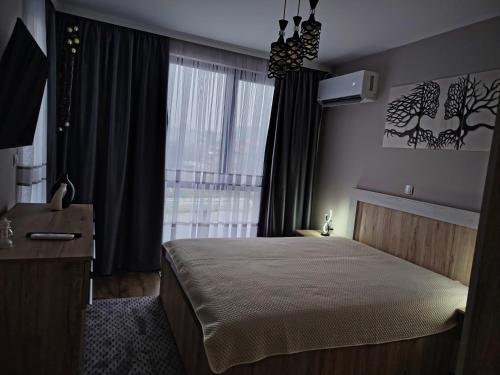 a bedroom with a bed and a large window at Апартамент Четири сезона 2 in Velingrad