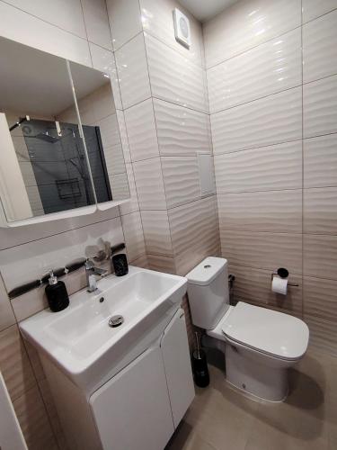 a bathroom with a white toilet and a sink at Апартамент Четири сезона 2 in Velingrad