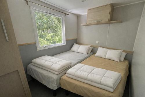 a small room with two beds and a window at Camping La Sensation in Matringhem
