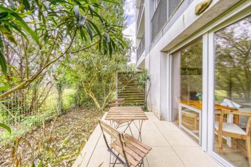 a patio with a table and chairs on a balcony at Jardins de Flore in Mérignac