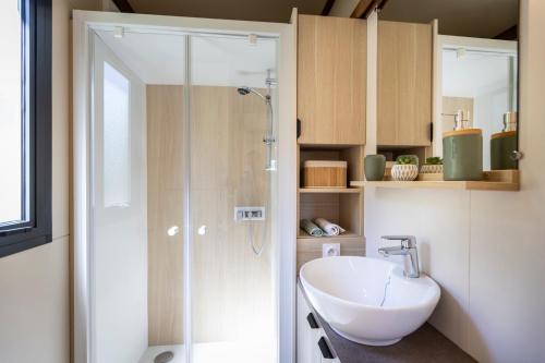 a bathroom with a shower and a white sink at Camping les vergers de Squividan *** in Tréffiagat