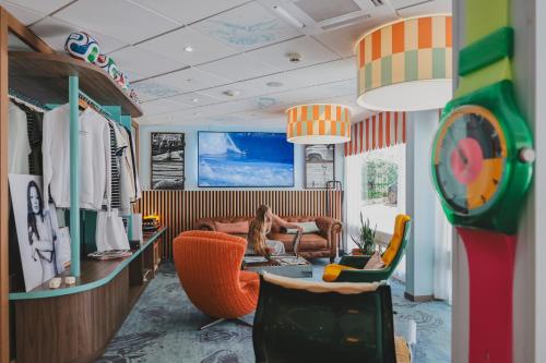 a living room with a woman sitting in a couch at Surf Club Hôtel by Akena - Grande plage in Biarritz