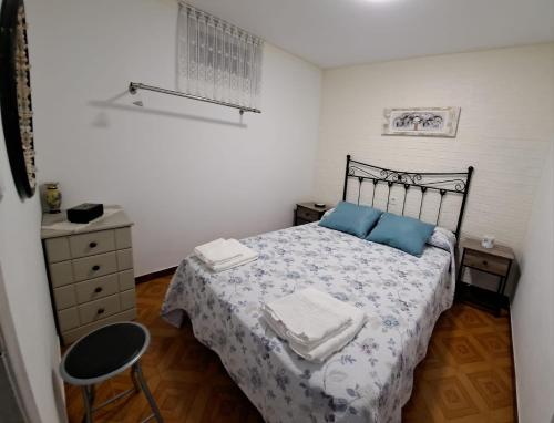 a bedroom with a bed with blue pillows and a chair at MERAKI in Fisterra