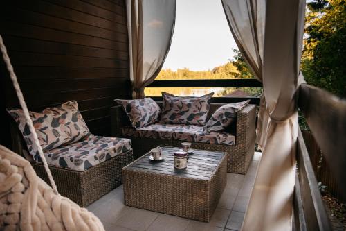 a porch with wicker chairs and a table at Augustów Willa Sóweczka in Sucha Rzeczka