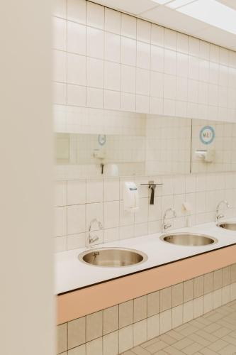 two sinks in a public bathroom with white tiles at Camping De Meidoorn in Sluis