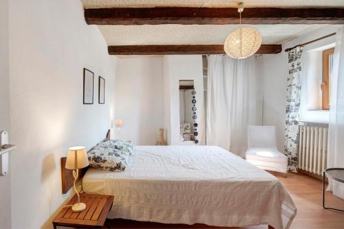 a white bedroom with a bed and a table at La Clé de l'Arboux in Mandagout