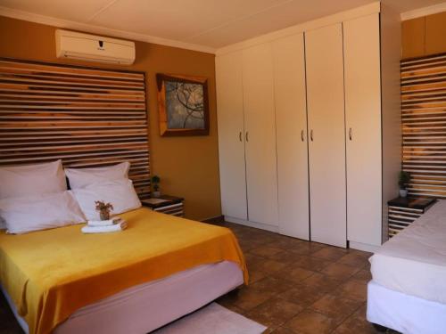 a bedroom with a bed and white cabinets at Oluzizi Guesthouse in Windhoek