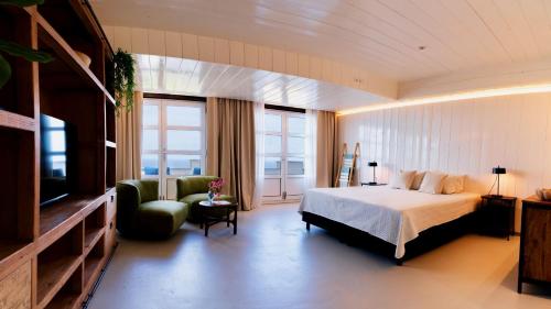 a bedroom with a bed and a couch and a television at Whale Tails Island Suites & Villas in Oranjestad