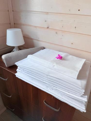 a pile of white sheets on a bed with a pink flower at Wakacje Bobolin in Bobolin