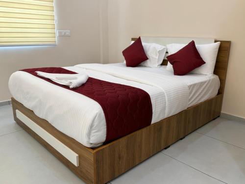 a bedroom with a large bed with white and red pillows at Misty Suite Infopark in Cochin