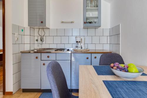 a kitchen with a table and chairs and a bowl of fruit at Apartmani Katica in Diklo