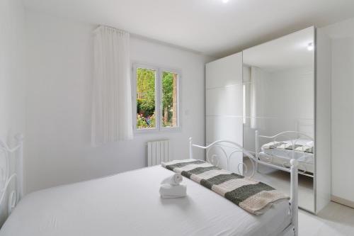 a white bedroom with a bed and a mirror at Maison du Périgord in Pazayac