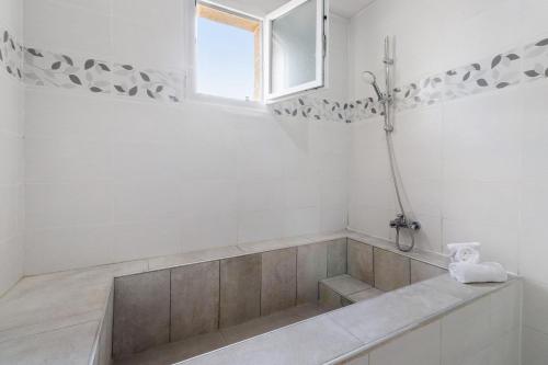 a white bathroom with a tub and a window at Maison du Périgord in Pazayac