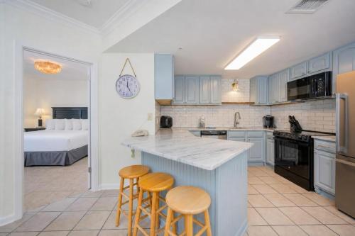a kitchen with two bar stools and a kitchen with a bed at Phoenix X 504 in Orange Beach
