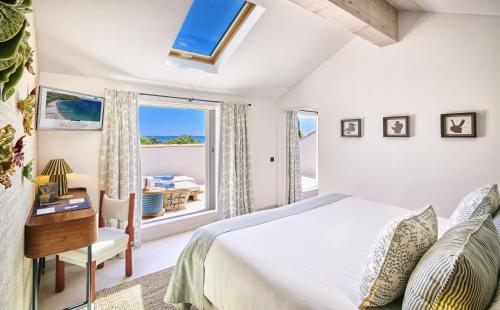 a bedroom with a bed and a window and a desk at La Ferme D'Augustin in Saint-Tropez
