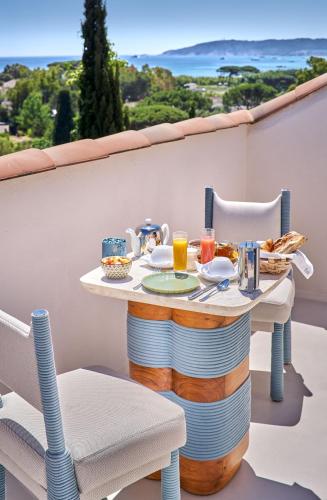a table with plates of food on a balcony at La Ferme D'Augustin in Saint-Tropez
