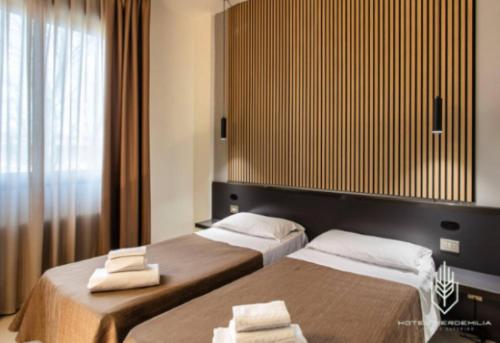 two beds in a hotel room with towels on them at Verdemilia Hotel in Anzola dell'Emilia