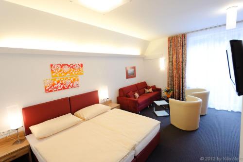 Habitación de hotel con cama y sofá rojo en Villa Nova - Hotel garni en Waidhofen an der Ybbs