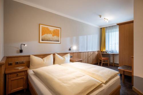 a hotel room with a large bed and a desk at Alpenresidenz-Sonnwend - Wellness Apartments nahe Zillertal Arena in Zell am Ziller