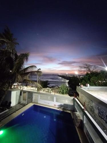 a swimming pool with a view of the ocean at night at Hotel El Emigrante in Puerto Colombia