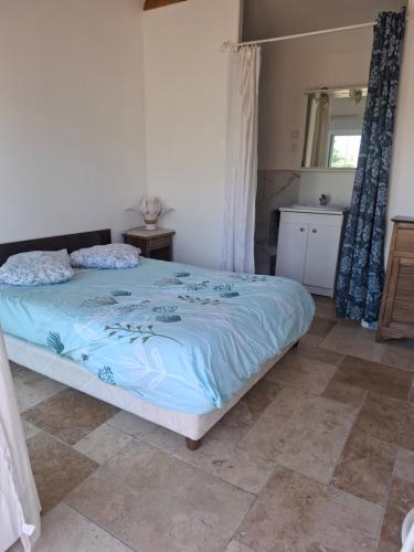 a bedroom with a bed with a blue comforter at Chambre in Lesparre-Médoc