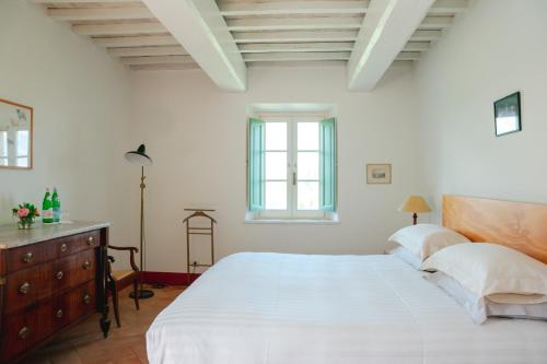a white bedroom with a large bed and a window at Dimora DiVino in Palazzone