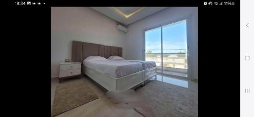 a bedroom with a bed and a large window at MAISON RITEl 1 in Taguermess