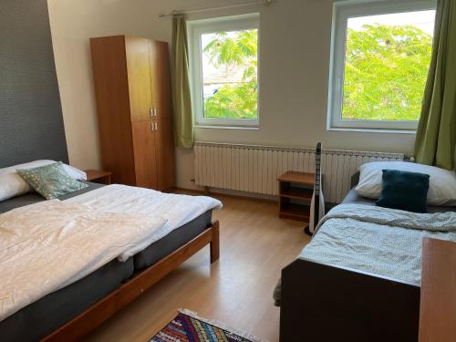 a bedroom with two beds and two windows at Téesz Vendégház in Zalaháshágy