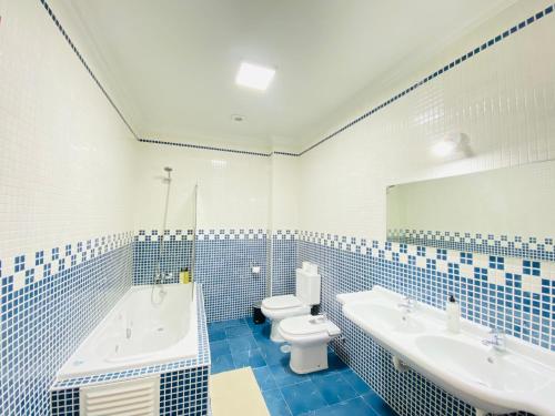 a blue tiled bathroom with a tub and a toilet at Aloha Burgau Guesthouse in Burgau