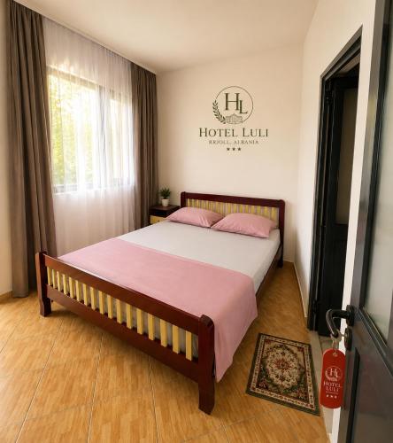 a bedroom with a large bed with pink pillows at Hotel LULI in Baks-Rrjoll