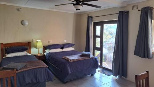 zwei Betten in einem Zimmer mit Fenster in der Unterkunft Declan House in Louis Trichardt
