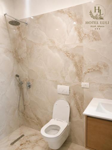 a bathroom with a toilet and a sink at Hotel LULI in Baks-Rrjoll