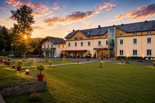 a group of buildings in a park at sunset at Carré Py' Hôtel in Bagnères-de-Bigorre