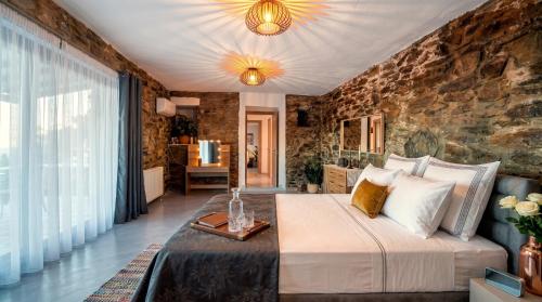 a bedroom with a large bed and a stone wall at Saronic Citadel Luxury Villa-Private Estate on Salamina Island in Salamina