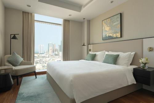 a bedroom with a large white bed and a chair at Fraser Suites Seef Bahrain in Manama