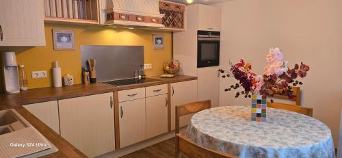 a kitchen with a table with a vase of flowers at La Maison Ôtrement in Martelange