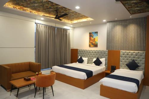 a hotel room with two beds and a chair at Hotel Pride Of Chittor in Chittaurgarh