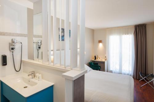 a bedroom with a bed and a sink and a window at The Originals Boutique, Hôtel Cassitel, Cassis in Cassis