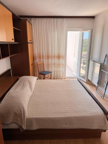 a bedroom with a large bed and a large window at Apartmani Ankica in Kampor