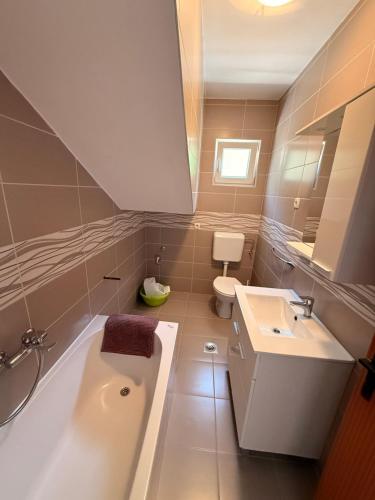 a bathroom with a tub and a toilet and a sink at Apartmani Ankica in Kampor