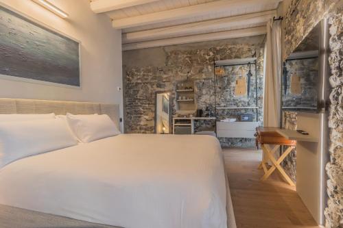 a bedroom with a white bed and a stone wall at La Corte Del Lario - Contrada Scoscesa in Varenna