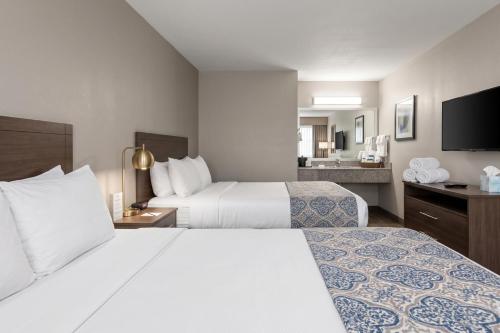 a hotel room with two beds and a flat screen tv at La Casa Inn Albany Near Tifton GA I 75 in Albany