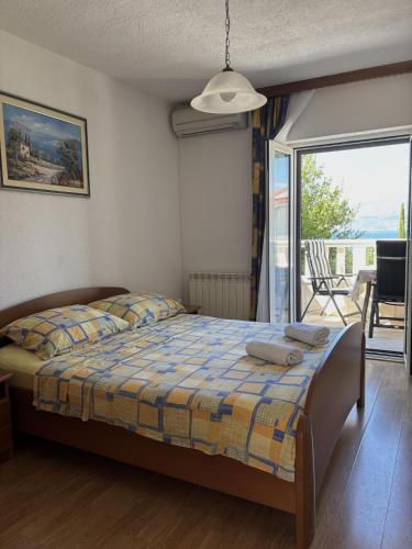 a bedroom with a bed and a balcony at Apartments Jela in Splitska