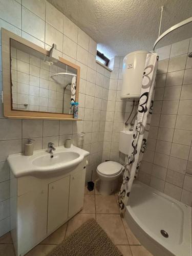 a bathroom with a sink and a toilet and a mirror at Apartments Jela in Splitska