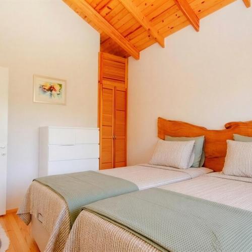 two beds in a room with white walls and wooden ceilings at Coollyhouse Keklik tepe Urla in Urla